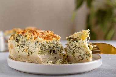 Geleneksel Fransız kiş Lorraine turtası, beyaz peynir ve ıspanak tabakta yenmeye hazır. Kapat.