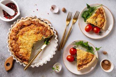 Taze pişmiş Lorraine turtası, beyaz peynir ve ıspanakla birlikte, parçalara ayrılıp, domates ve otlarla servis ediliyor, yemeye hazır. Üst yaşam