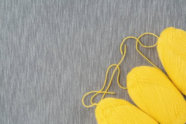 2021 Renk Eğiliminin Gösterimi. Gri arka planda örgü örmek için üç sarı iplik. Kopyalama alanı olan üst görünüm