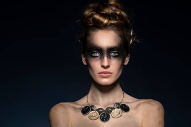 Bir punk modelinin karanlık yaratıcı makyajı. Mavi arka planda çok güzel poz veriyor. Geri dönüşümlü malzeme ve güzellik konseptiyle yapılmış bir kolyesi var. Boşluğu kopyala 