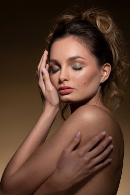 Çekici bir genç kız, yakın plan güzellik portresi, bej arka planda saç stili, yüzüne yakın elleri ve kapalı gözleri var, tatlı bir kadın..