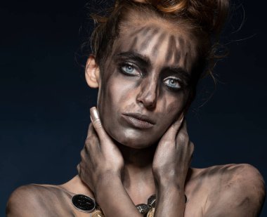 Siyah kirli makyajlı punk tarzıyla atartik genç bir kadin, caera modasina uygun bir sekilde bakiyor ve geri donusumden bir gerdanlik takiyor.