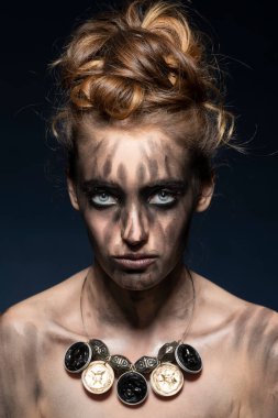 Yaratıcı, siyah makyajlı, güzel, şehvetli bir kız. Mavi, koyu renk arka planda çekici gözlerle poz veriyor. 