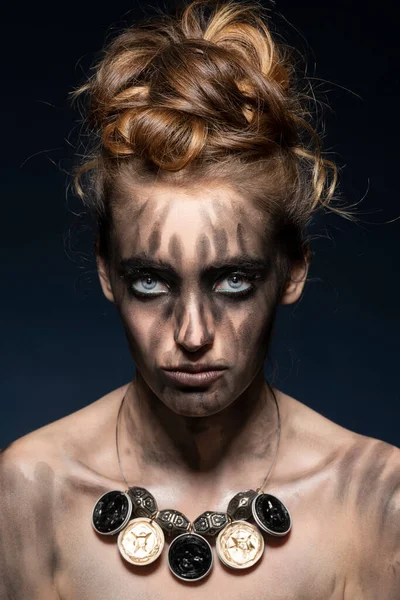 Yaratıcı, siyah makyajlı, güzel, şehvetli bir kız. Mavi, koyu renk arka planda çekici gözlerle poz veriyor. 