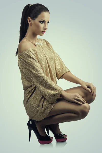 Menina em vestido de ouro está olhando em frente — Fotografia de Stock