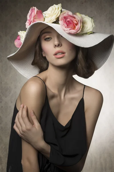 Menina deslumbrante com flores no chapéu — Fotografia de Stock