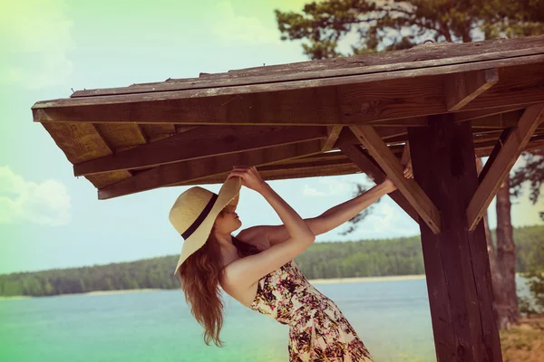 Playing girl ner lake with summer hat — Stockfoto