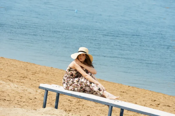 Sweet girl on beach with hat resting — ストック写真