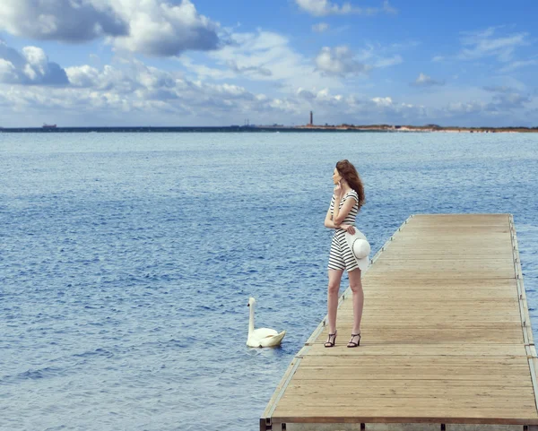 Girl on pier with swan — Stock Photo, Image