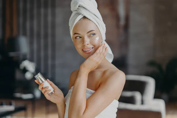 Indoor Shot Mujer Joven Sonriente Aplica Crema Hidratante Cara Cuida — Foto de Stock