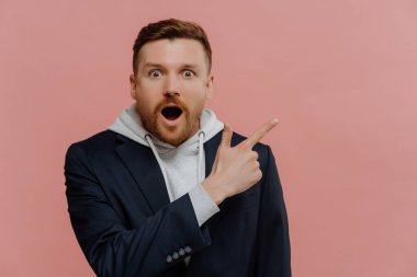 Şok olmuş genç adam sağ üst köşeyi işaret ediyor ve şaşırıyor.