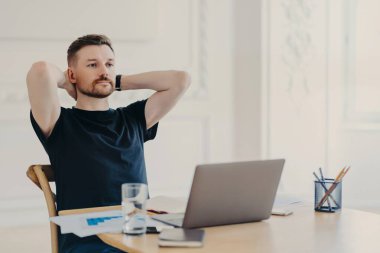 Genç işadamı iş yerinde dizüstü bilgisayarla otururken işten zevk alıyor