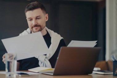 Evden uzakta çalışan odaklanmış işadamı, belgeye bakıyor