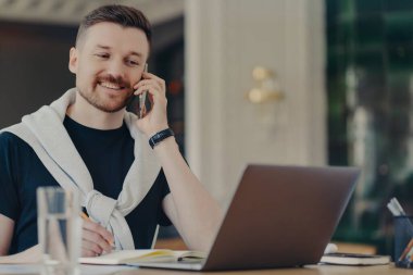 Evden çalışırken cep telefonuyla konuşan mutlu iş adamı.