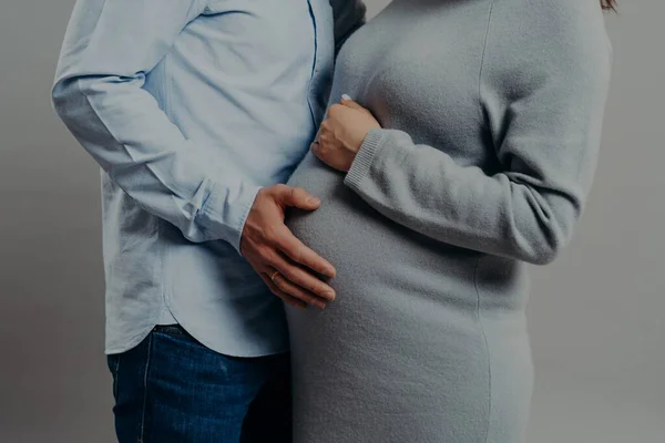 怀孕的妻子穿着连衣裙,与摸她大肚子的丈夫很像.未来的母亲和父亲都在等待新的家庭成员。父母身份的概念 — 图库照片