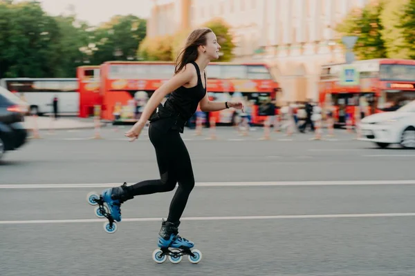 Mujer europea en buena forma física paseos en rodillos rollos en patines en línea vestida con desgaste activo tiene descanso activo. Concepto de estilo de vida deportivo — Foto de Stock