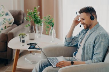 Smiling handsome man staring intently at laptop screen at home