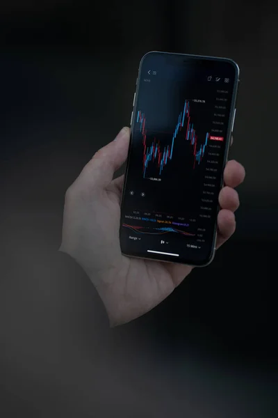 Мужчина держит смартфон с графиком финансового форекс на экране — стоковое фото