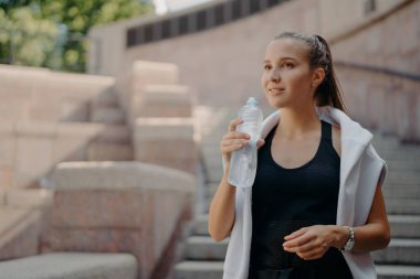 At kuyruklu atlet kadın, kardiyo eğitiminden sonra susar. İçecekler şişeden alınır. İçecekler susuz kalmaz.
