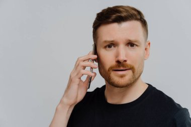 Endişeli bir adam cep telefonuyla tatsız bir konuşma yapıyor ve kendini mutsuz hissediyor.