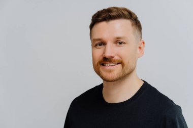 Kameraya gülümseyen ve pozitifliğini ifade eden yakışıklı, tıraşsız adam.