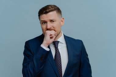 Sinirli iş adamı yumruğunu ısırıyor ve kameraya bakıyor.