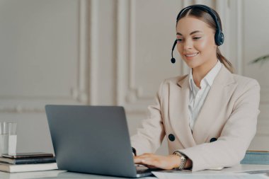 Takım elbiseli başarılı iş kadını iş arkadaşı ile internette konuşuyor.