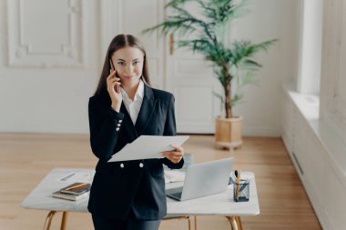 Pozitif genç iş kadını iş arkadaşıyla telefonda konuşuyor.