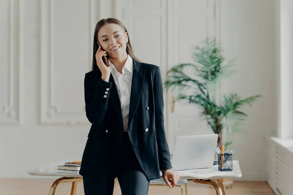 Sonriente joven atractiva mujer de negocios de pie y hablando por teléfono — Foto de Stock