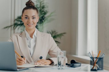 Genç başarılı kadın serbest yazar not defterine bilgi yazıyor.