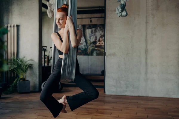 Snella giovane donna con pratiche di capelli rossi anti-gravità fly yoga — Foto Stock
