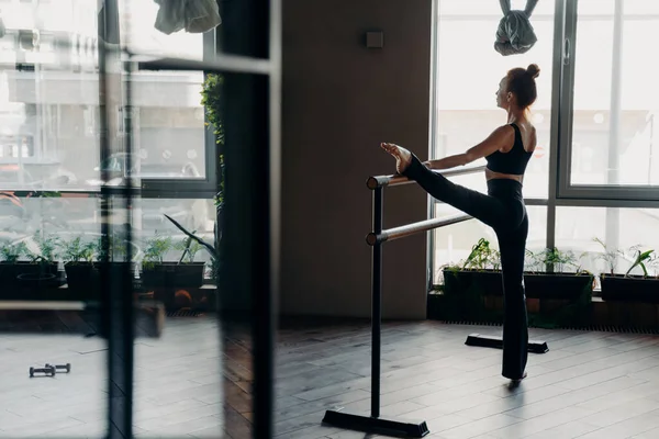 Slim ballerina durante la sua routine di stretching accanto sulla barra di balletto in studio — Foto Stock