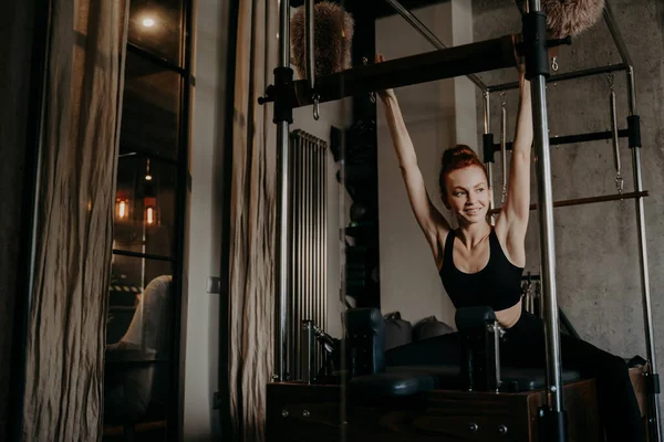 Giovane donna atletica stretching corpo su pilates cadillac riformatore — Foto Stock