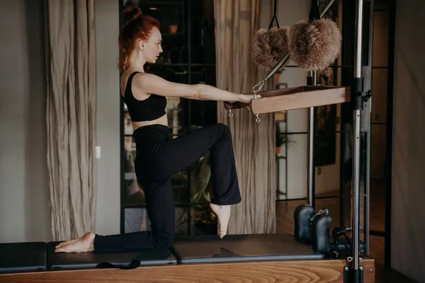 Slender fit pilates trainer menunjukkan latihan peregangan pada reformator cadillac — Stok Foto