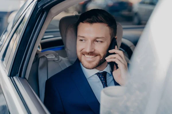 Image de jeune juriste caucasien à succès en costume bleu foncé formel parlant sur téléphone portable en voiture — Photo