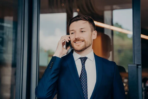 Jovem empresário de terno azul falando no telefone e sorrindo — Fotografia de Stock