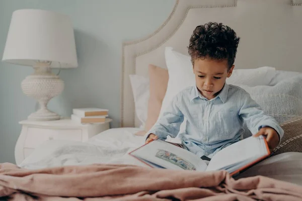 Милий афроамериканець, маленький хлопчик, який намагається читати книжку "Діти". — стокове фото