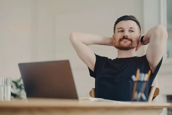 Glad affärsman vilar efter jobbet medan han sitter på sin arbetsplats hemma — Stockfoto