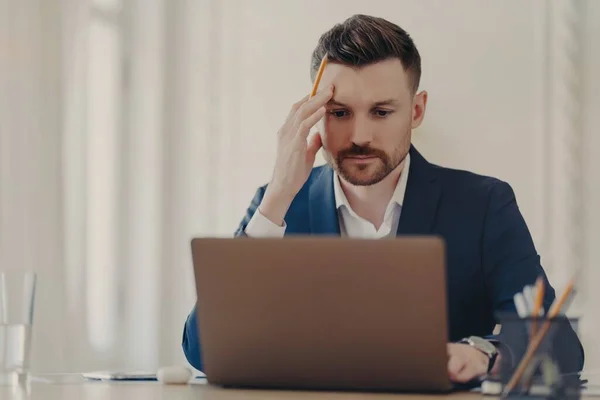 Pensando di business executive seduto alla sua scrivania di fronte al computer portatile — Foto Stock