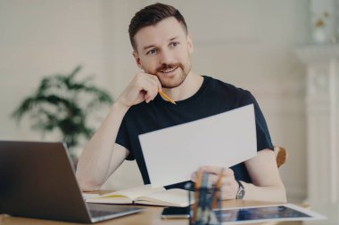 Yakışıklı Avrupalı işadamının, modern teknolojilerle çevrili iç mekanda kağıt belgeler bulundurmasına sevindim. Bilgiler, uzak mesafelere özenle yapılmış gibi görünüyor.