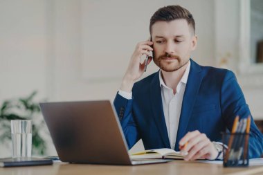 Ciddi bir iş adamı masaüstü pozisyonunda dizüstü bilgisayarla yapılan telefon görüşmelerini yoğunlaştırıyor. Günlük planlarına, resmi giysiler içinde yoğun çalışma saatlerine notlar yazıyor. Dijital yönetim