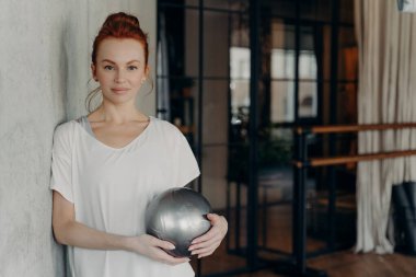 Spor salonunda spor yaparken kızıl saçlı genç bayan dinleniyor.