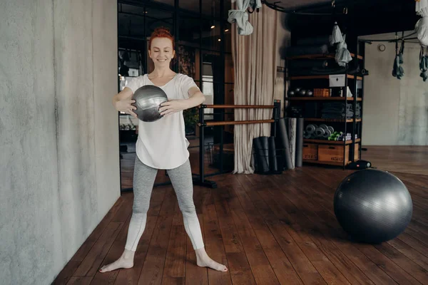 Giovane donna in forma con i capelli rossi godendo barrette allenamento con piccola palla fitness — Foto Stock