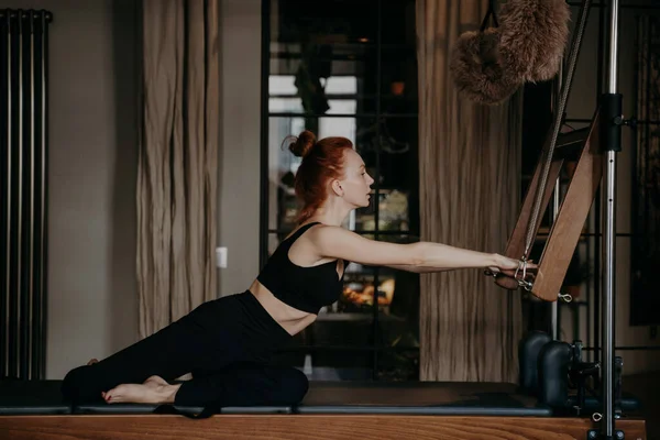 Femme gingembre sportive étirant le corps athlétique sur réformateur cadillac pendant l'entraînement de pilates — Photo