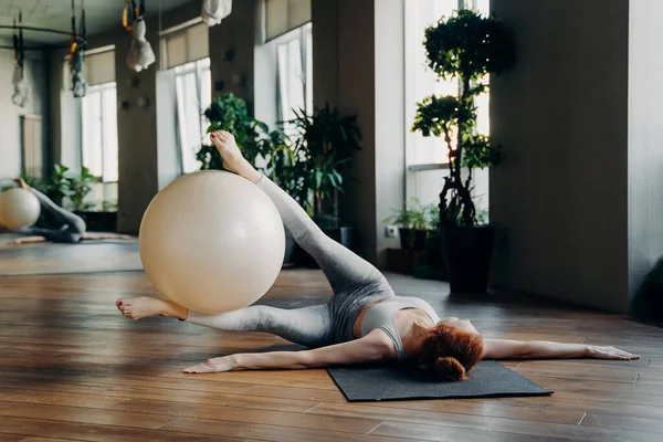 Donna che fa esercizi addominali con palla in forma su tappetino yoga — Foto Stock