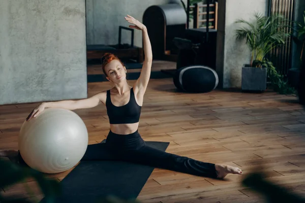 Fiatal lány ül osztott helyzetben közben pilates edzés — Stock Fotó