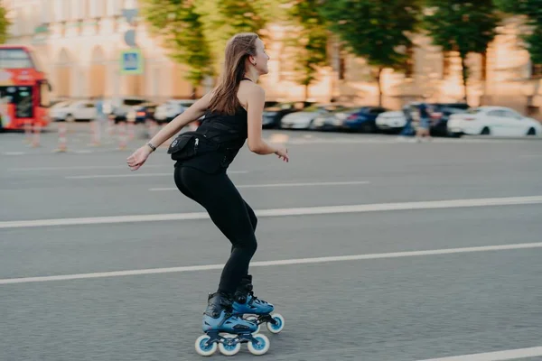 Aktivní životní styl a hobby koncept. Sporty mladá žena dělá sport venku vyjížďky na kolečkových bruslích oblečený ve sportovních šatech má fitness aktivity pózuje v městském místě na silnici. Kolečkové brusle. — Stock fotografie