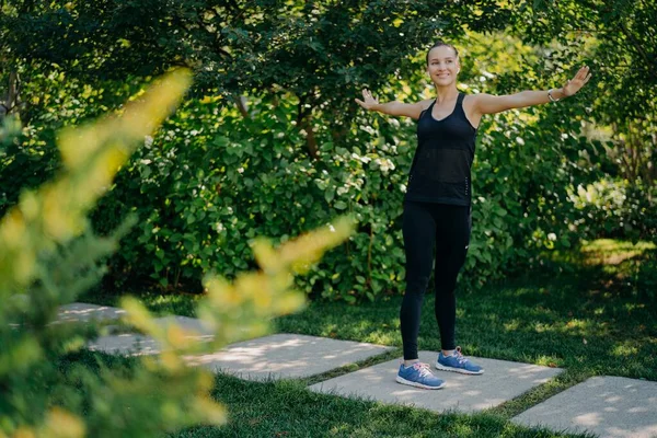 運動フィットの屋外ショット若い女性は腕を横に良い気分の演習では、屋外のスポーツウェアは新鮮な空気と美しい自然を楽しんでいる腕を維持します。温暖化や運動の概念 — ストック写真