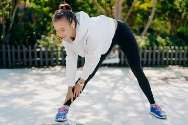 やる気のある若い大人の女性は定期的に足に手に達するスポーツのために行く足の肩幅離れて着用スポーツウェアは、減量のためのトレーニング屋外スポーツ活動を楽しむ — ストック写真