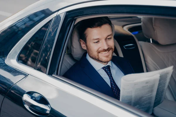 Beau jeune banquier en costume de smoking formel intelligent lit journal dans l'automobile de luxe — Photo